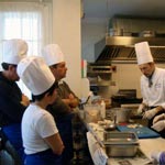 Alcuni partecipanti osservano ed apprendono le tecniche di preparazione dei piatti